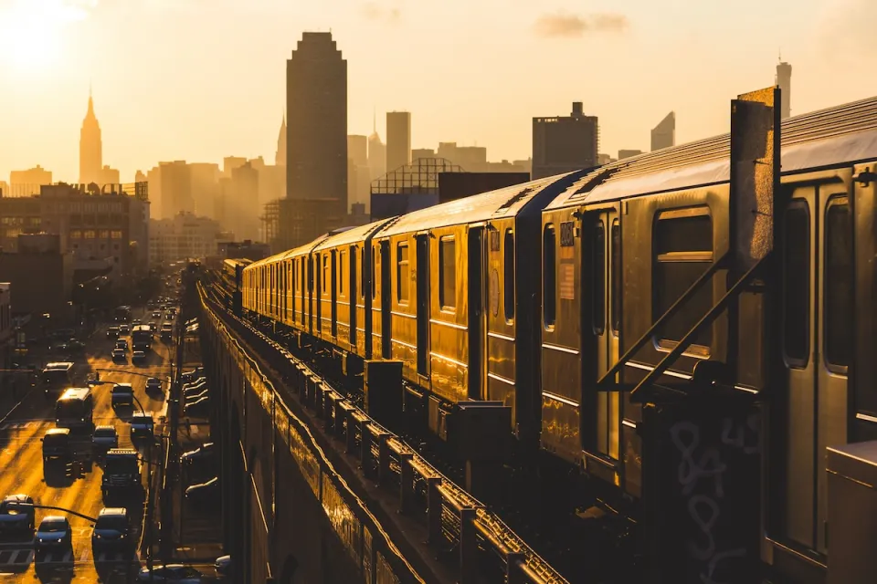 New York City subway train on elevated track in yellow light.